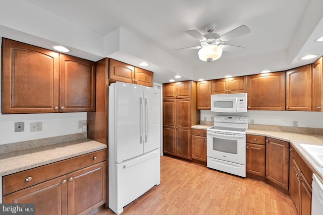 kitchen featuring white appliances, brown cabinetry, and light wood finished floors