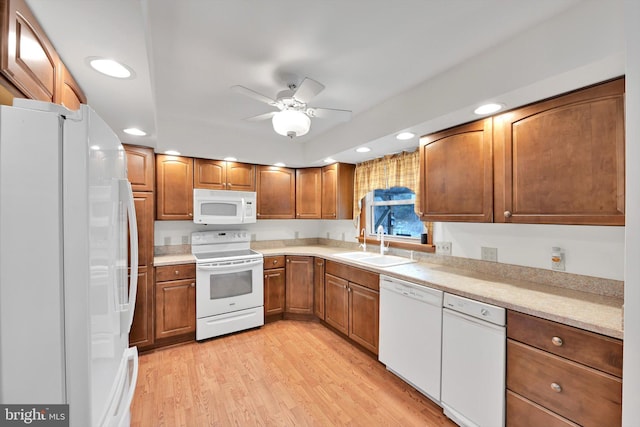 kitchen featuring light wood-style flooring, a ceiling fan, a sink, white appliances, and light countertops