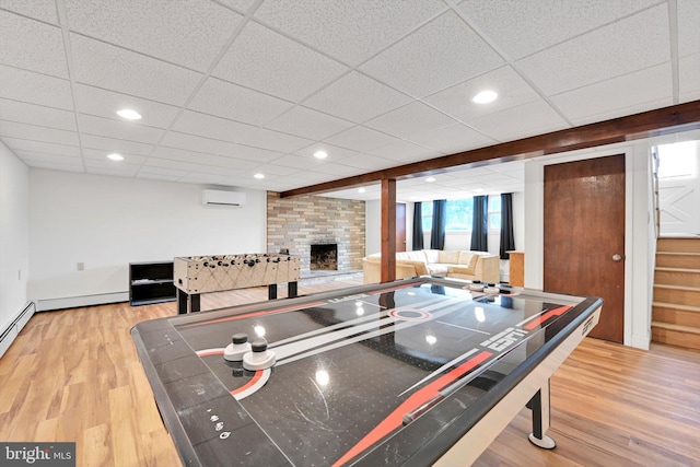 recreation room featuring recessed lighting, an AC wall unit, wood finished floors, and a fireplace