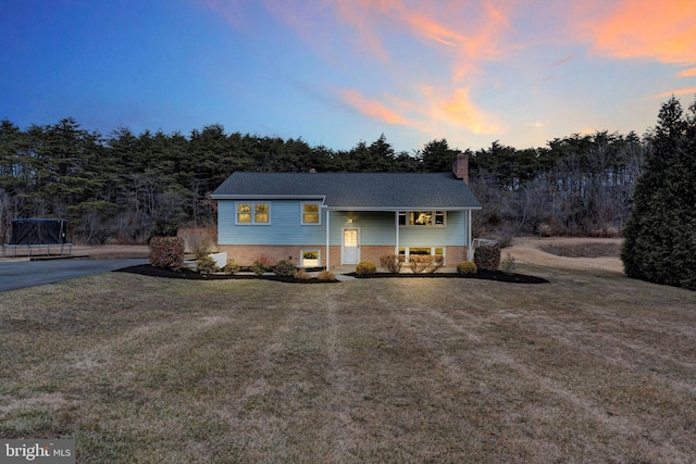 bi-level home featuring brick siding, a chimney, and a front lawn