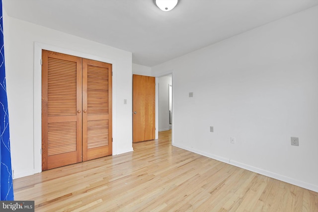 unfurnished bedroom featuring wood finished floors, a closet, and baseboards