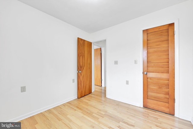 unfurnished bedroom with light wood-style flooring and baseboards