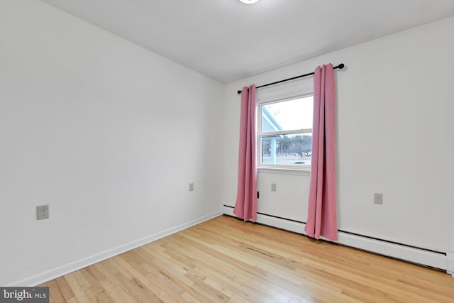 spare room with light wood-type flooring, baseboards, and a baseboard radiator