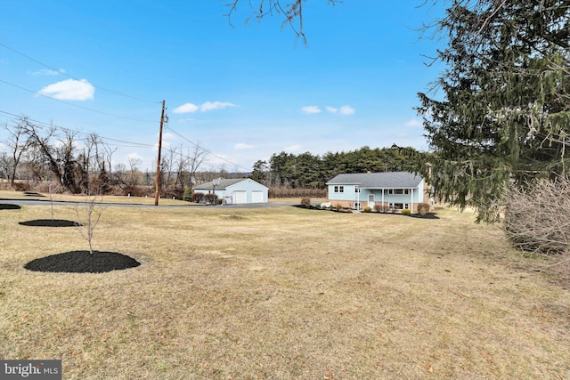 view of yard with covered porch, driveway, a detached garage, and an outdoor structure