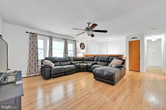 living room featuring baseboards, light wood-type flooring, and a ceiling fan