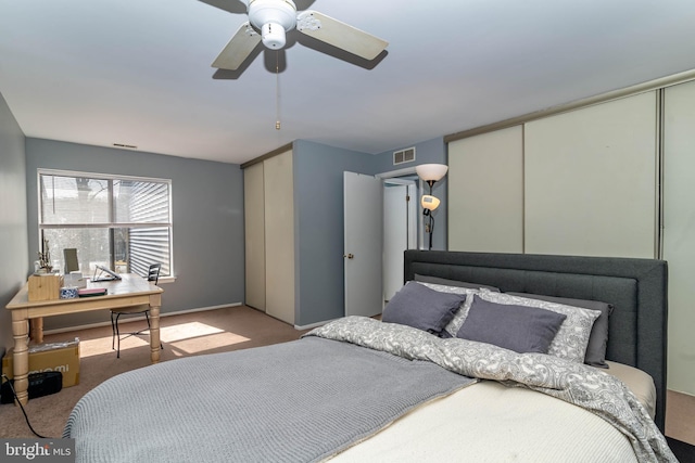 carpeted bedroom featuring visible vents, two closets, and ceiling fan