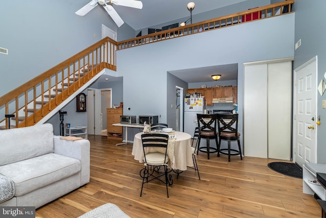 living room with stairway, ceiling fan, visible vents, and light wood-style floors