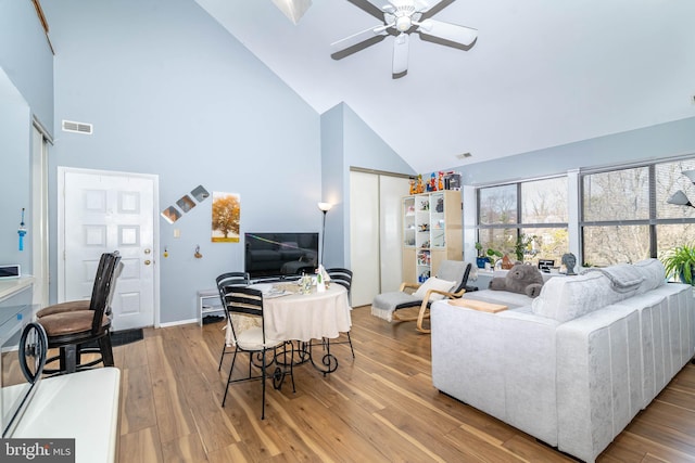 living area featuring ceiling fan, visible vents, high vaulted ceiling, and wood finished floors