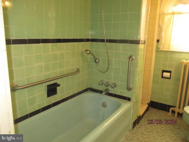 bathroom featuring walk in shower, tile walls, a tub to relax in, and toilet