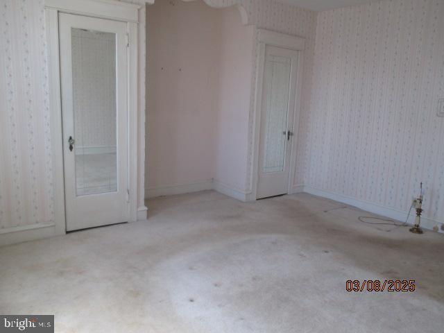 unfurnished room featuring wallpapered walls and baseboards