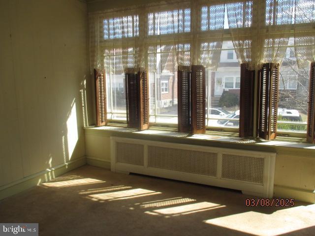 unfurnished room featuring radiator heating unit and a healthy amount of sunlight