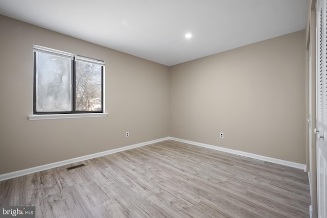 spare room featuring visible vents, baseboards, and light wood finished floors