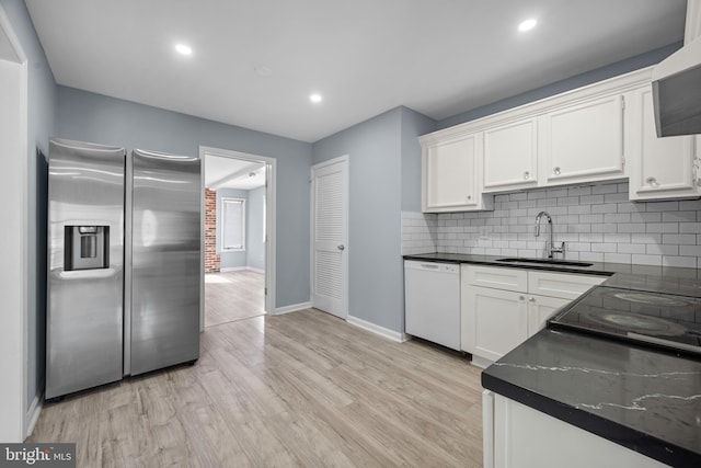 kitchen with dark countertops, dishwasher, stainless steel refrigerator with ice dispenser, and a sink