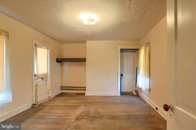 unfurnished bedroom featuring baseboard heating, a textured ceiling, baseboards, and wood finished floors