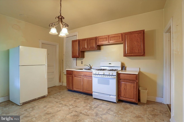 kitchen featuring brown cabinetry, light countertops, hanging light fixtures, white appliances, and a sink