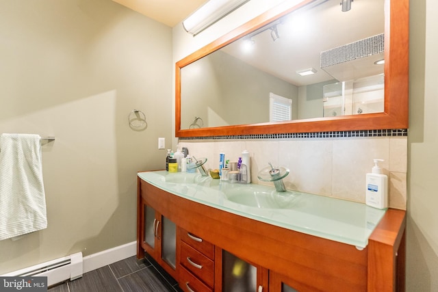 full bathroom featuring double vanity, baseboards, baseboard heating, and a sink