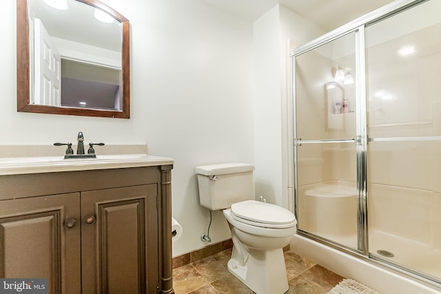 full bathroom with baseboards, vanity, a shower stall, and toilet