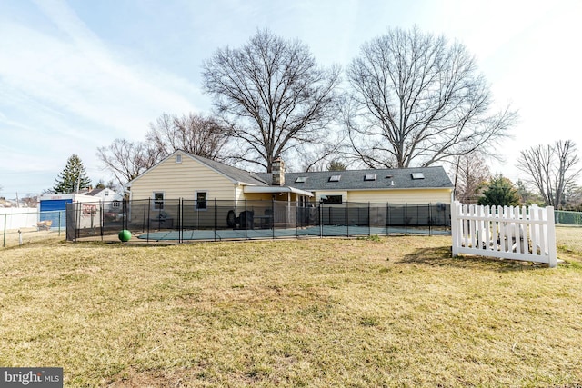 rear view of property featuring a lawn and fence