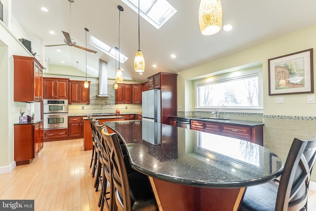 kitchen with a large island, a sink, appliances with stainless steel finishes, island range hood, and dark brown cabinets