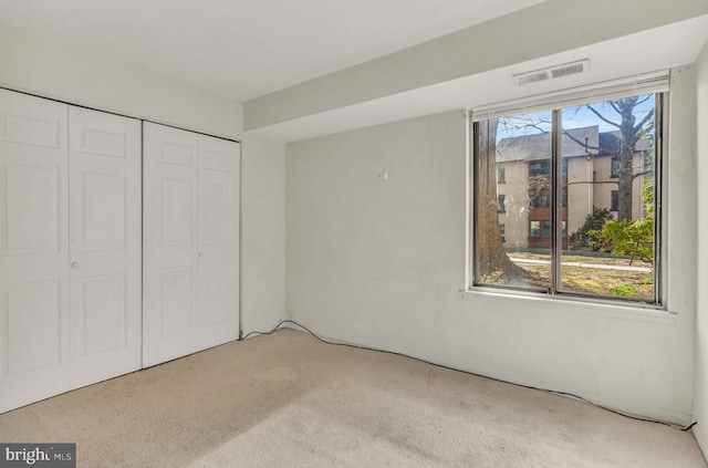 unfurnished bedroom with a closet, carpet flooring, and visible vents