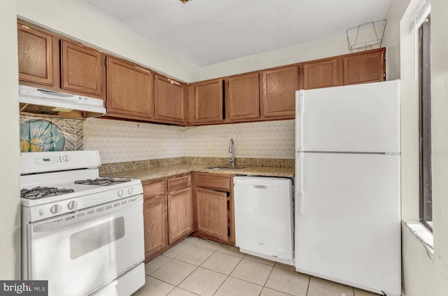 kitchen with under cabinet range hood, a sink, white appliances, light countertops, and light tile patterned floors