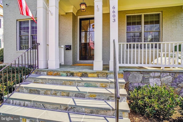 view of exterior entry featuring brick siding and a porch