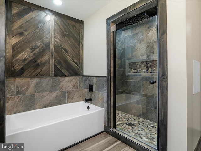 bathroom featuring a bath, a stall shower, and wood finished floors