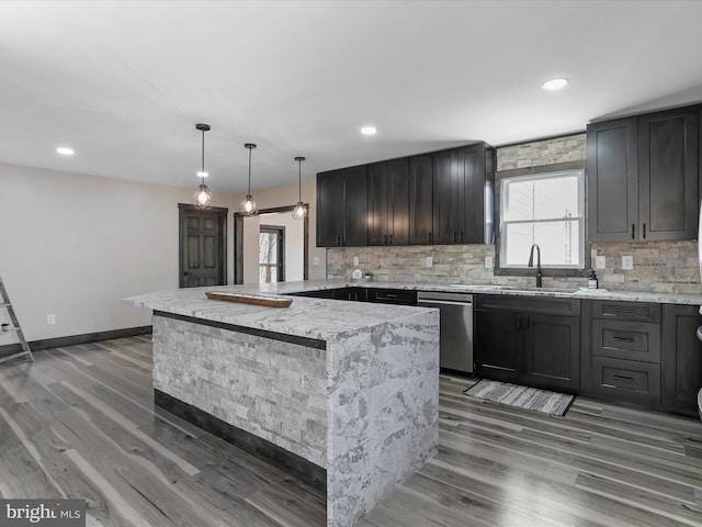 kitchen with stainless steel dishwasher, a peninsula, backsplash, and a sink