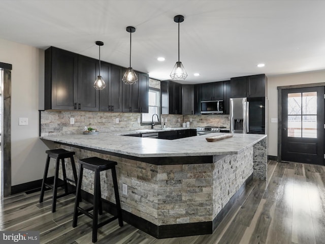 kitchen featuring a peninsula, dark wood-style floors, tasteful backsplash, and stainless steel appliances