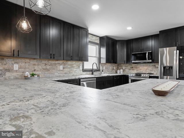 kitchen with a sink, tasteful backsplash, dark cabinetry, appliances with stainless steel finishes, and hanging light fixtures