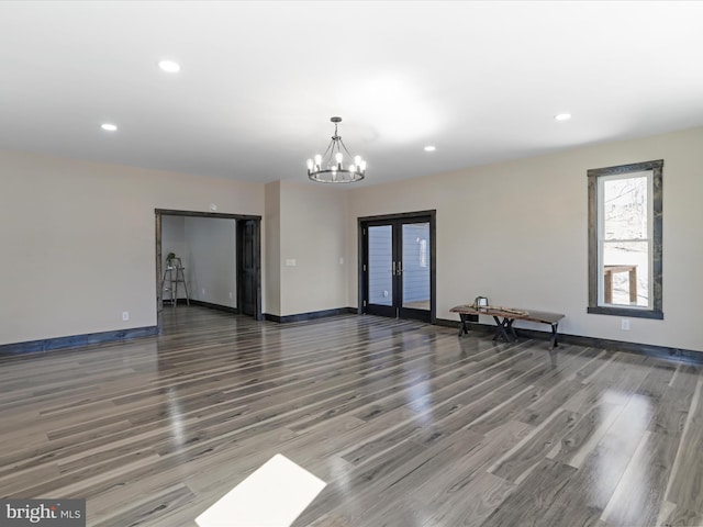 spare room featuring baseboards, recessed lighting, french doors, wood finished floors, and a notable chandelier