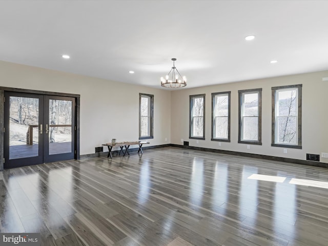 spare room featuring wood finished floors, french doors, visible vents, and a chandelier