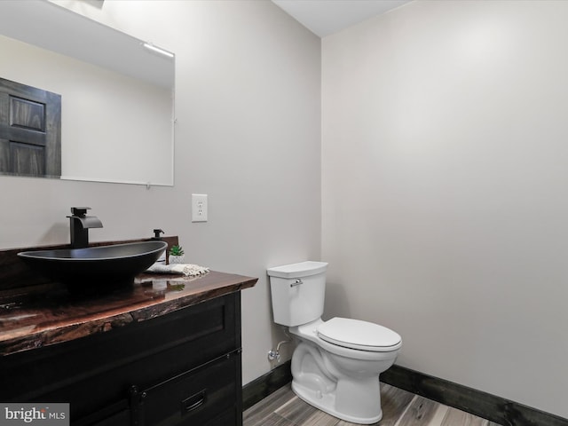 bathroom featuring vanity, toilet, wood finished floors, and baseboards