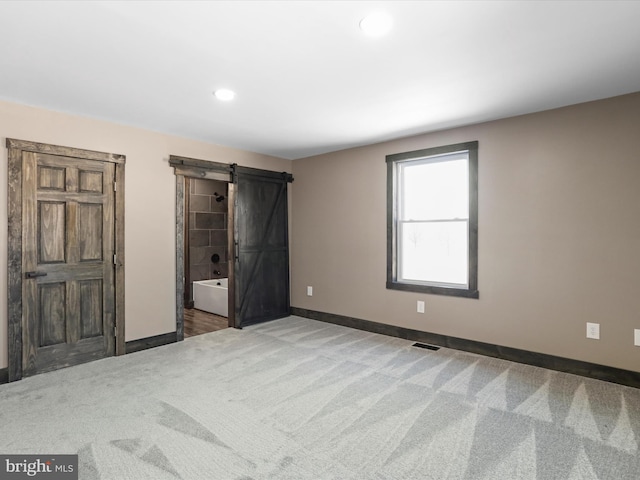 unfurnished bedroom with baseboards, visible vents, recessed lighting, a barn door, and carpet flooring