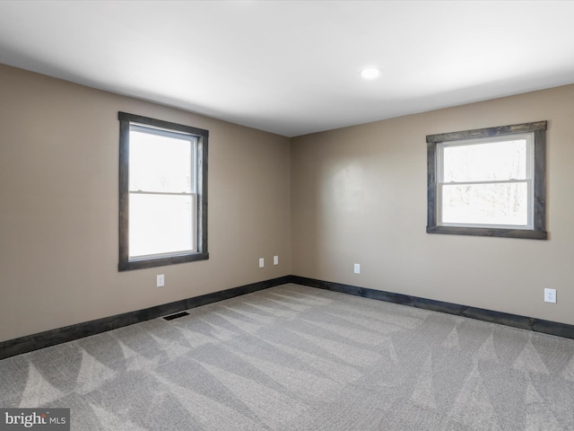 carpeted spare room featuring visible vents and baseboards