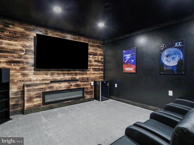 home theater room featuring a glass covered fireplace, carpet, and baseboards