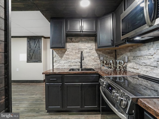 kitchen with dark countertops, stainless steel microwave, electric range, and a sink