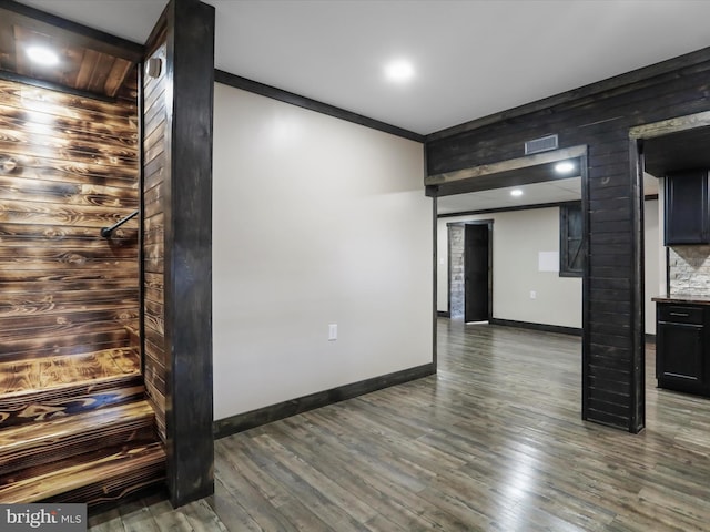 empty room with dark wood-style floors, visible vents, and baseboards