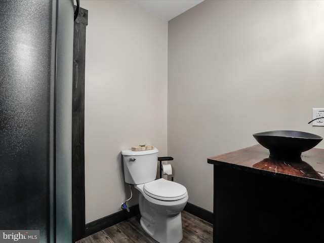 bathroom with vanity, toilet, wood finished floors, and baseboards