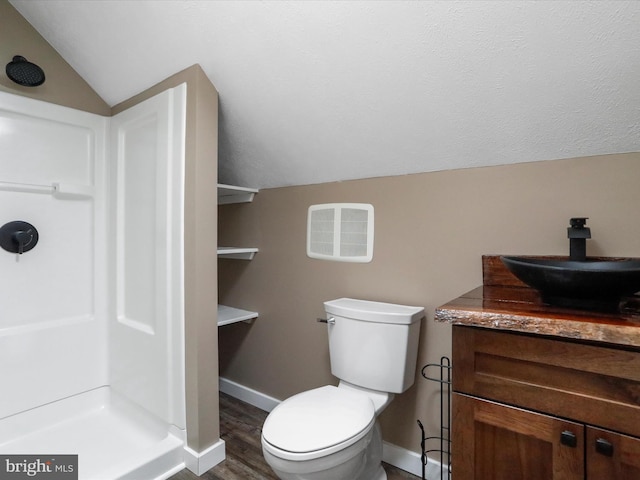 bathroom with vanity, baseboards, lofted ceiling, a stall shower, and toilet