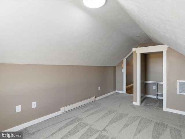 additional living space featuring carpet, baseboards, a baseboard radiator, lofted ceiling, and a textured ceiling