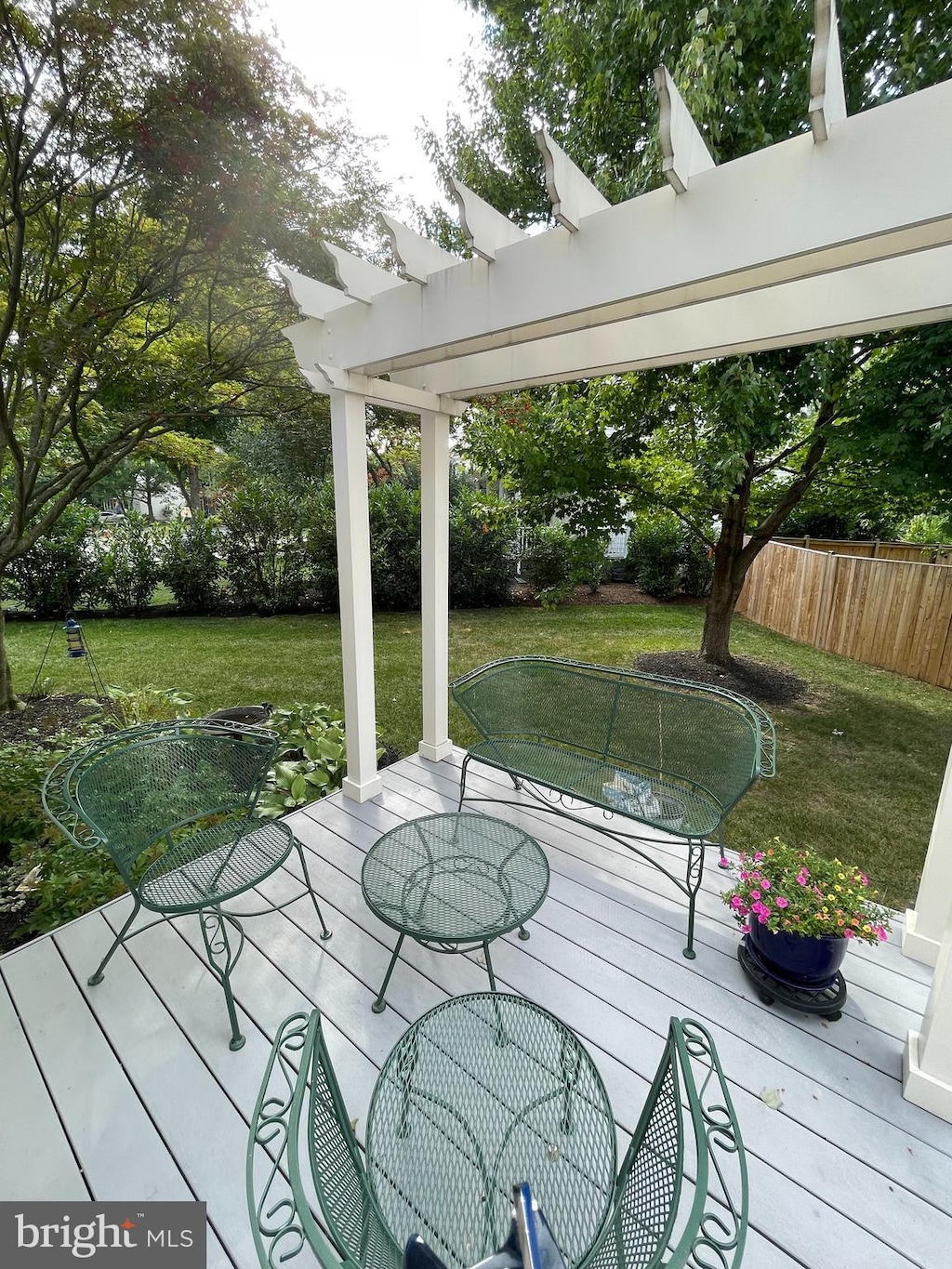 wooden deck featuring outdoor dining space, a lawn, a pergola, and fence