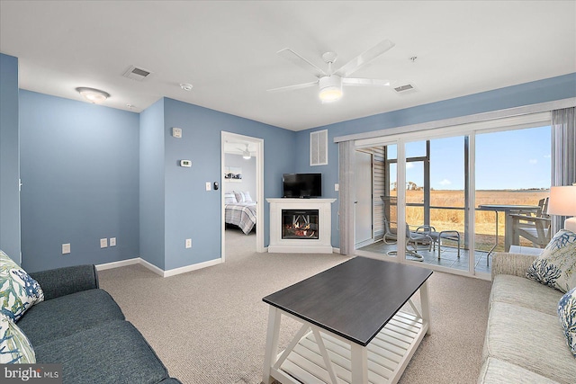 living area with carpet flooring, visible vents, baseboards, and ceiling fan