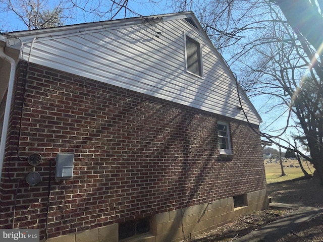 view of side of home featuring brick siding and crawl space