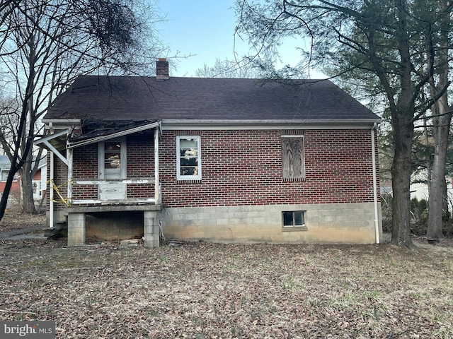 view of property exterior with brick siding, a chimney, and roof with shingles