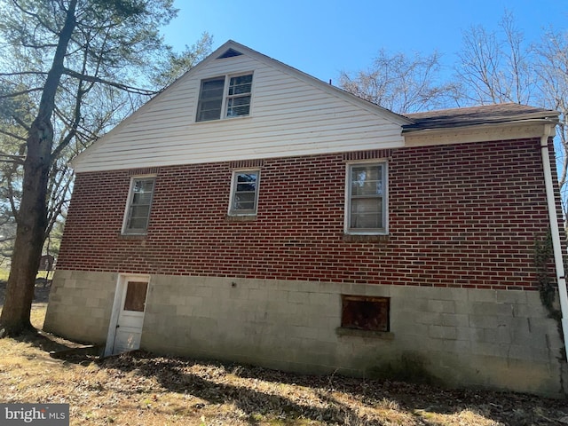 view of home's exterior with brick siding and a shingled roof