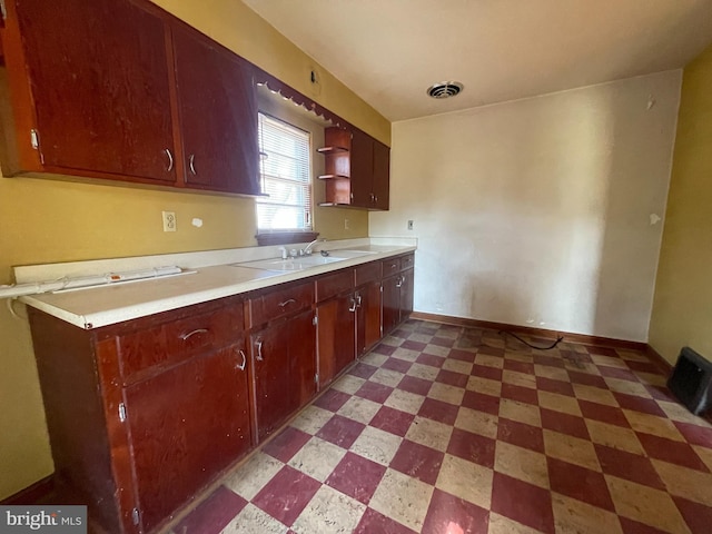 kitchen featuring visible vents, a sink, open shelves, baseboards, and light floors