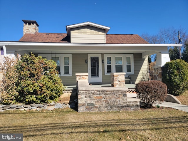 bungalow featuring a porch, a front lawn, and a chimney