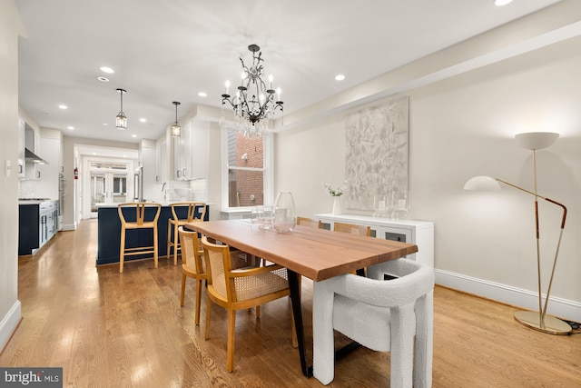 dining area with baseboards, recessed lighting, light wood-type flooring, and a chandelier