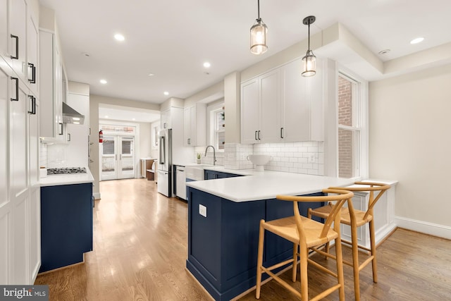 kitchen with a sink, appliances with stainless steel finishes, a breakfast bar, and light wood finished floors